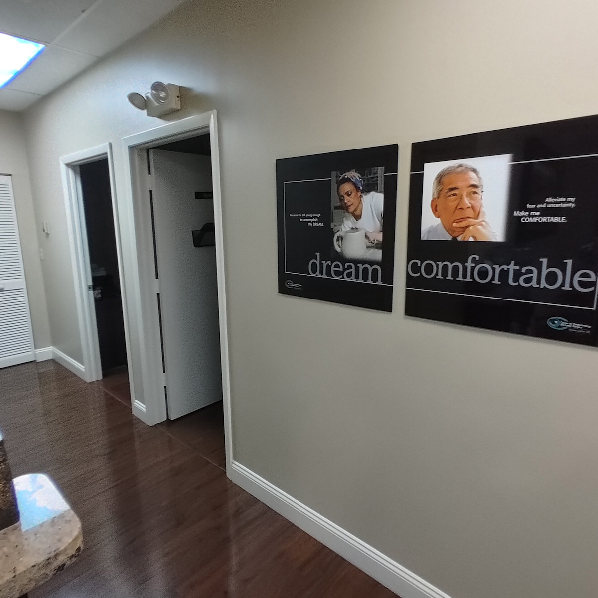 The image shows a professional office environment with wall-mounted signs featuring two individuals, likely professionals, and text promoting comfort and dreaming.