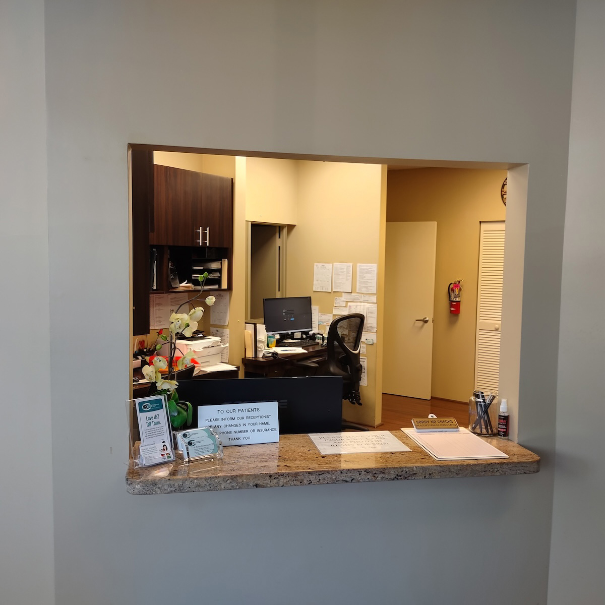 The image depicts an interior view of a reception area with a desk, a computer monitor, a keyboard, and a mouse.