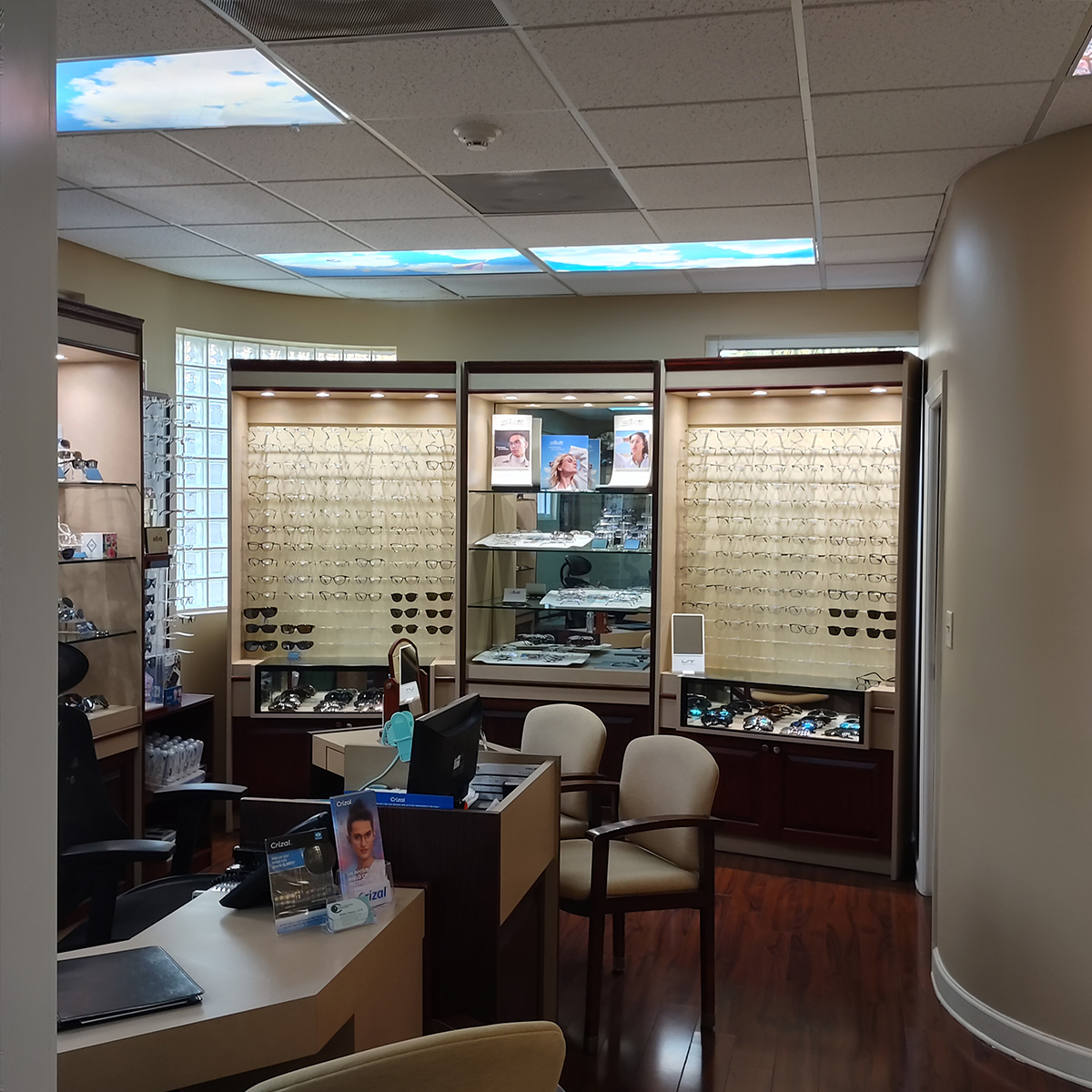 An optometry office with a large display case showcasing various eyeglasses and frames, framed by two columns and featuring a glass door.