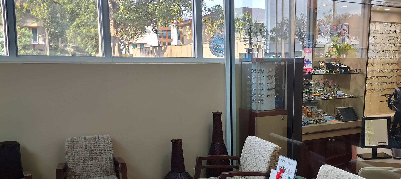 The image shows an interior space, specifically a waiting area with chairs, a counter with display cases, and a window with blinds partially drawn.