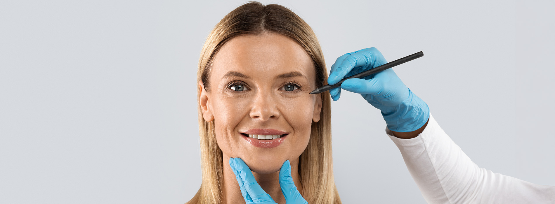 A woman receiving skin treatment at a beauty salon with a technician applying a mask to her face.