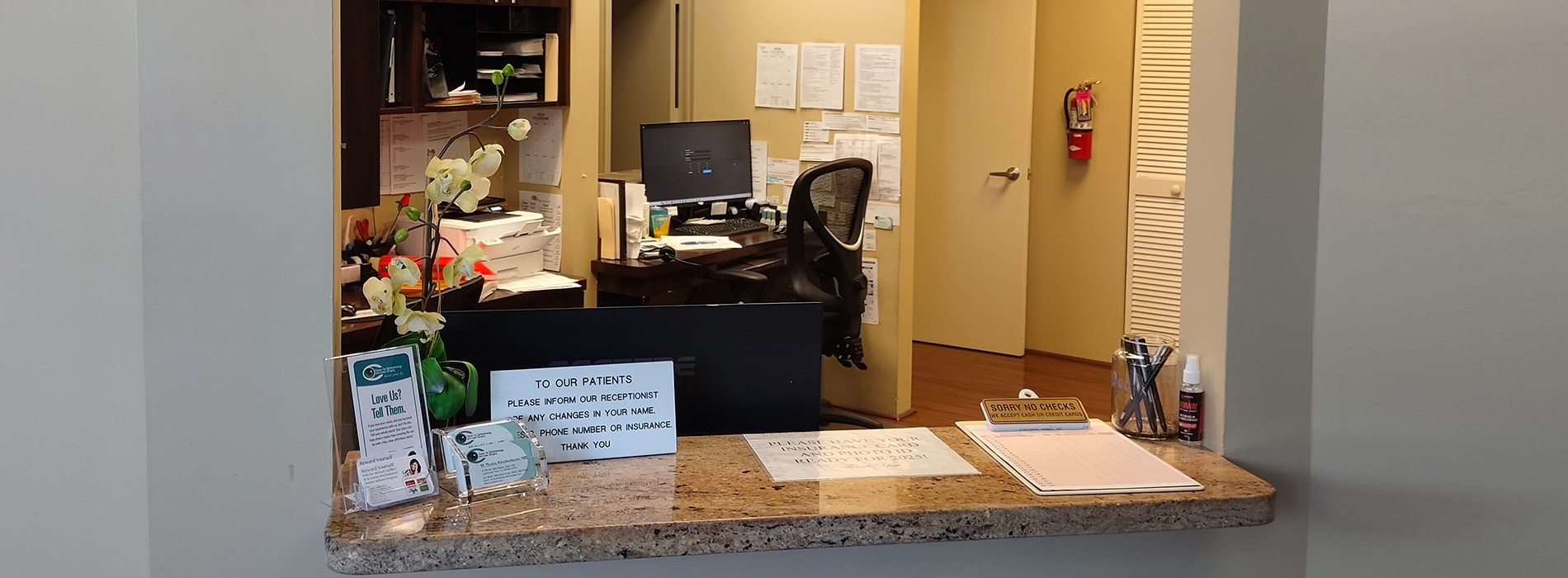 The image shows an interior view of a reception area with a counter, a sign indicating services provided, and a person seated behind the counter.