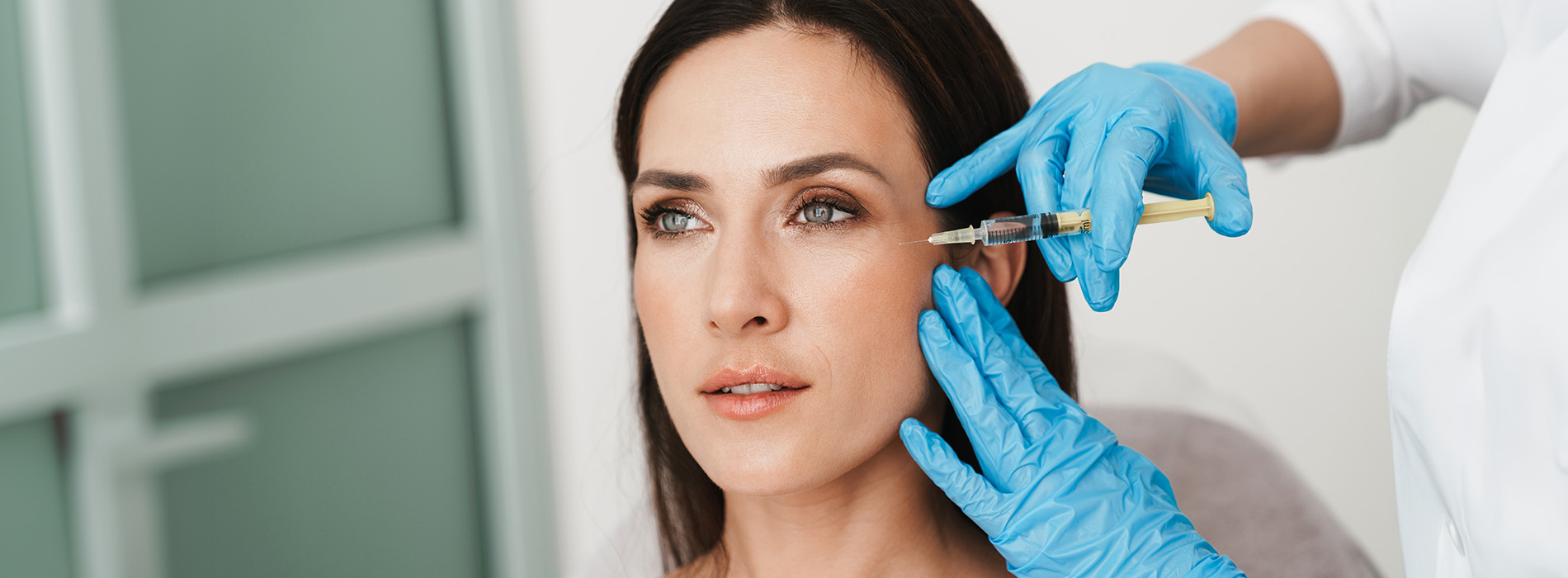 A woman receiving cosmetic treatment from a professional in a medical setting.