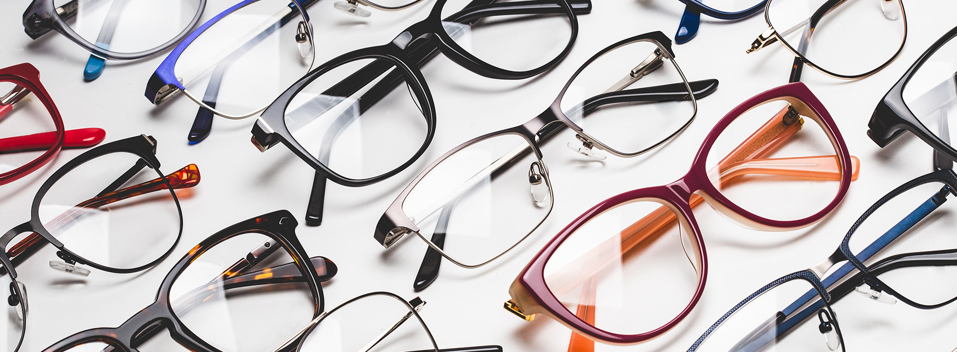 The image shows a collection of eyeglasses with various frame colors displayed against a white background.