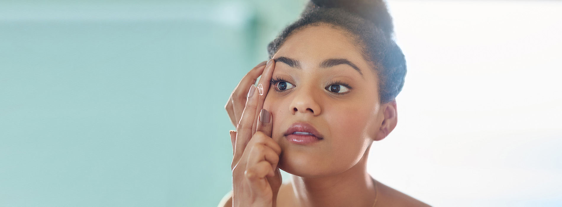 A woman applying makeup with her eyes closed.