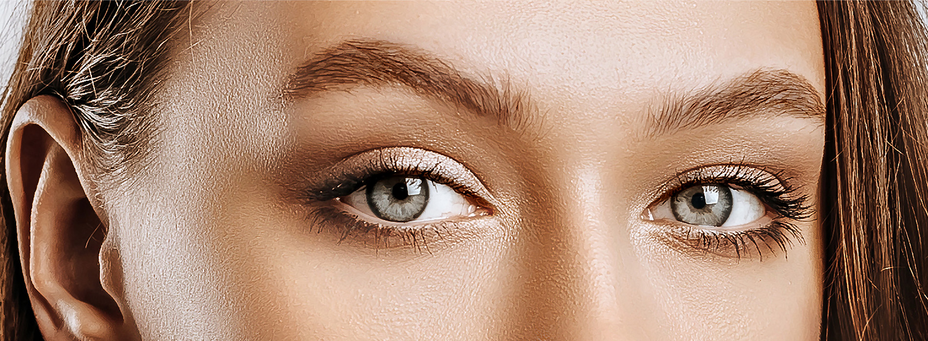 The image shows a close-up of a person s face with striking blue eyes, set against a neutral background.