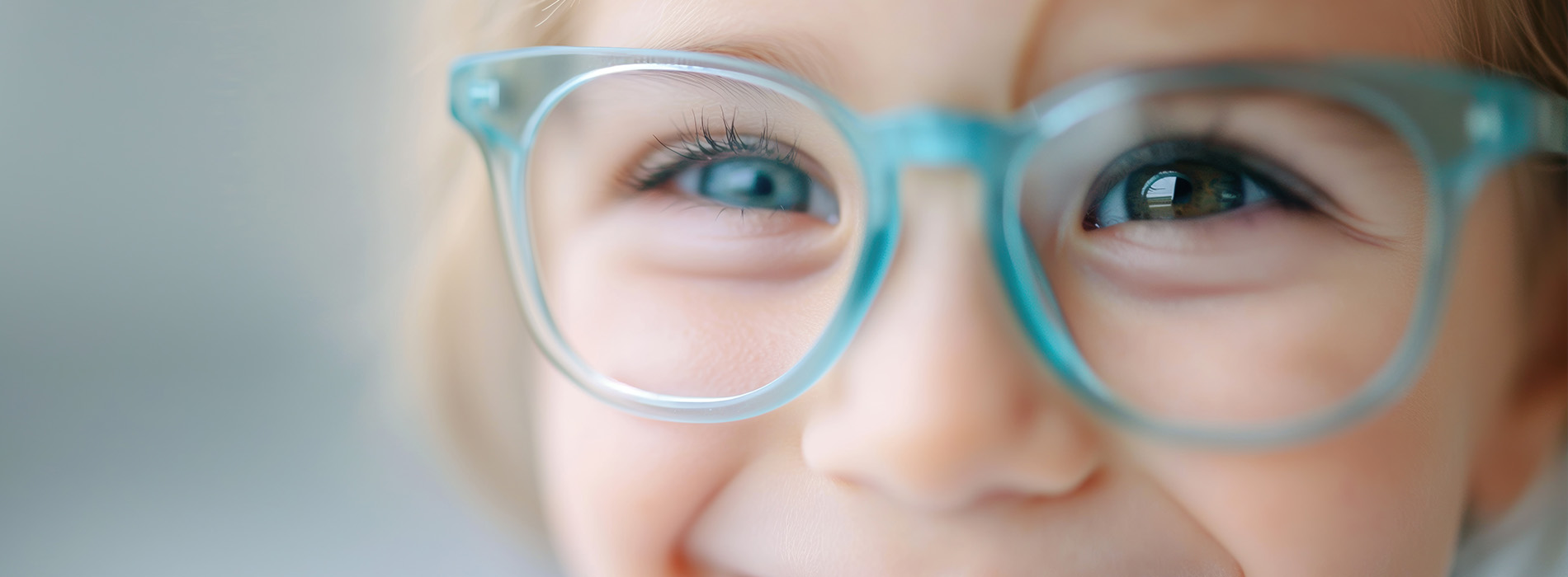 A young child wearing glasses and smiling at the camera.