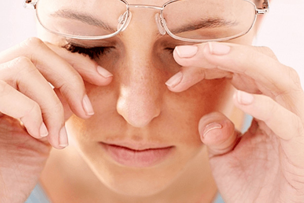 Woman with glasses rubbing her eyes, possibly indicating fatigue or deep thought.