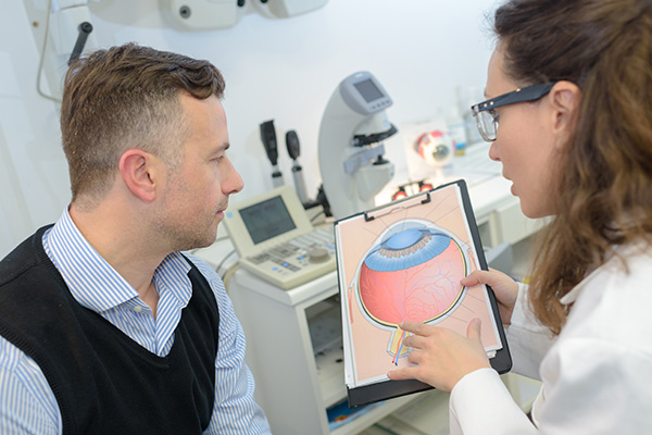 A man is seated at a medical examination table with a woman standing beside him, both attentively examining an image on a tablet screen.