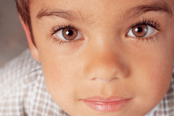 The image shows a young child with light brown hair and blue eyes looking directly at the camera.