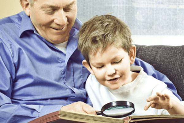 A man and a child are seated together on a couch, engaged with a book.