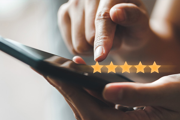 The image shows a person s hand holding a smartphone with a star rating icon displayed on its screen.