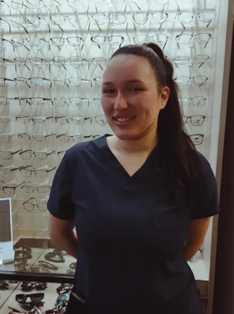 A woman wearing glasses and standing in front of a display of eyeglasses.