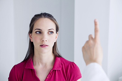 The image shows a woman with a neutral expression looking slightly away from a man who appears to be pointing at her face, suggesting an examination or consultation scenario.