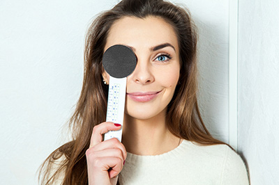 A woman holding a measuring tape with her face partially obscured by the tape s end.